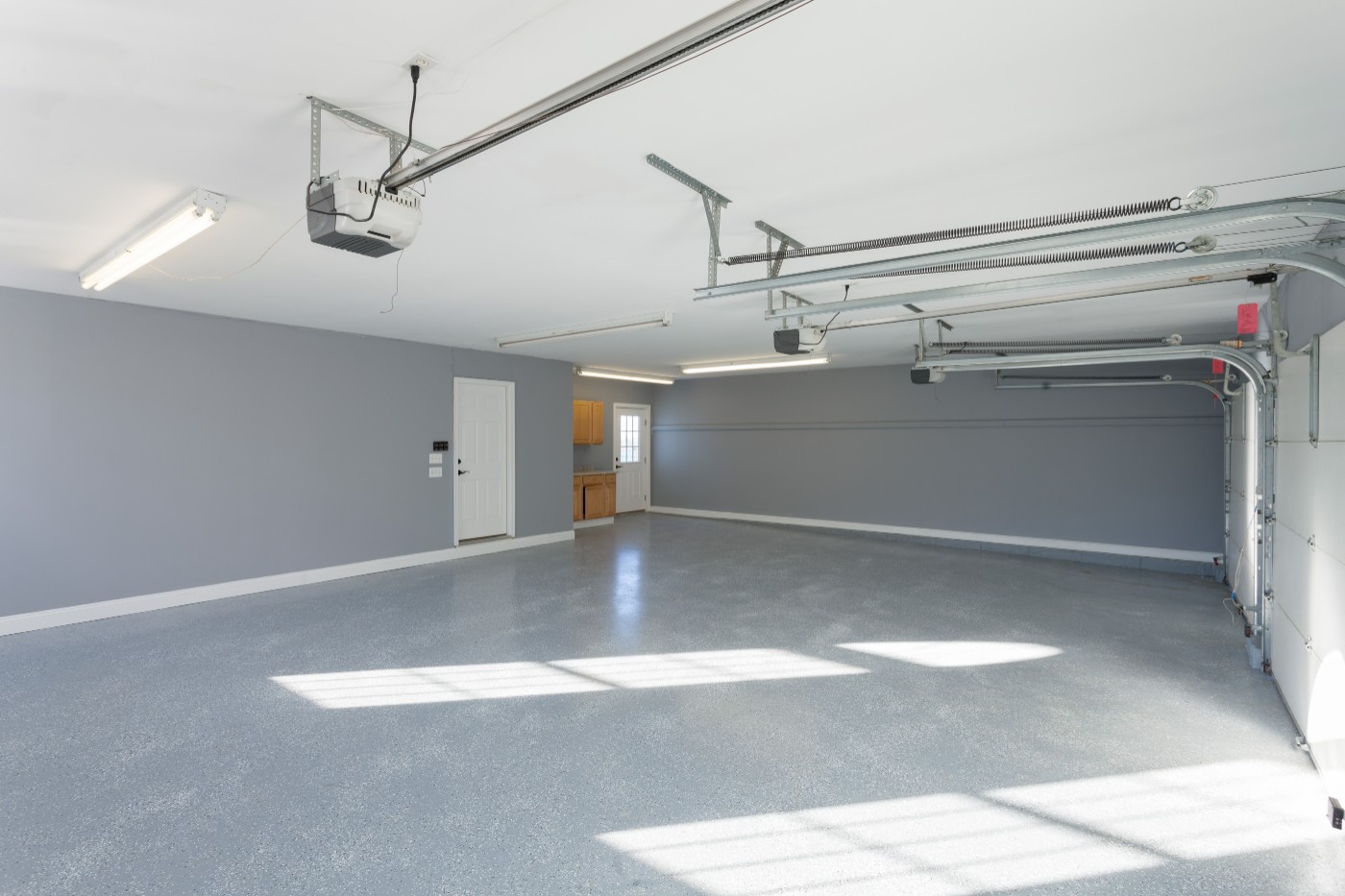 Clean, spacious garage interior with gray epoxy flooring and overhead door opener system