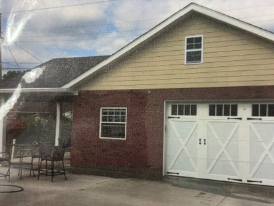 Red brick house with white garage doors and tan upper level siding