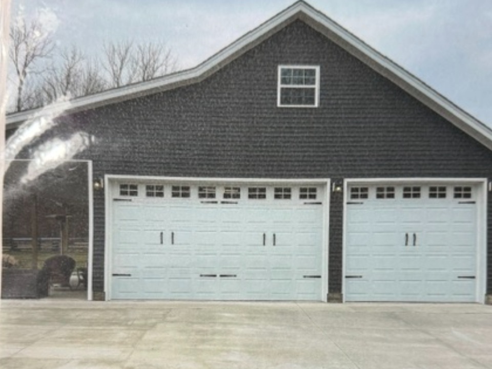 Dark brick garage with two white panel doors and upper windows