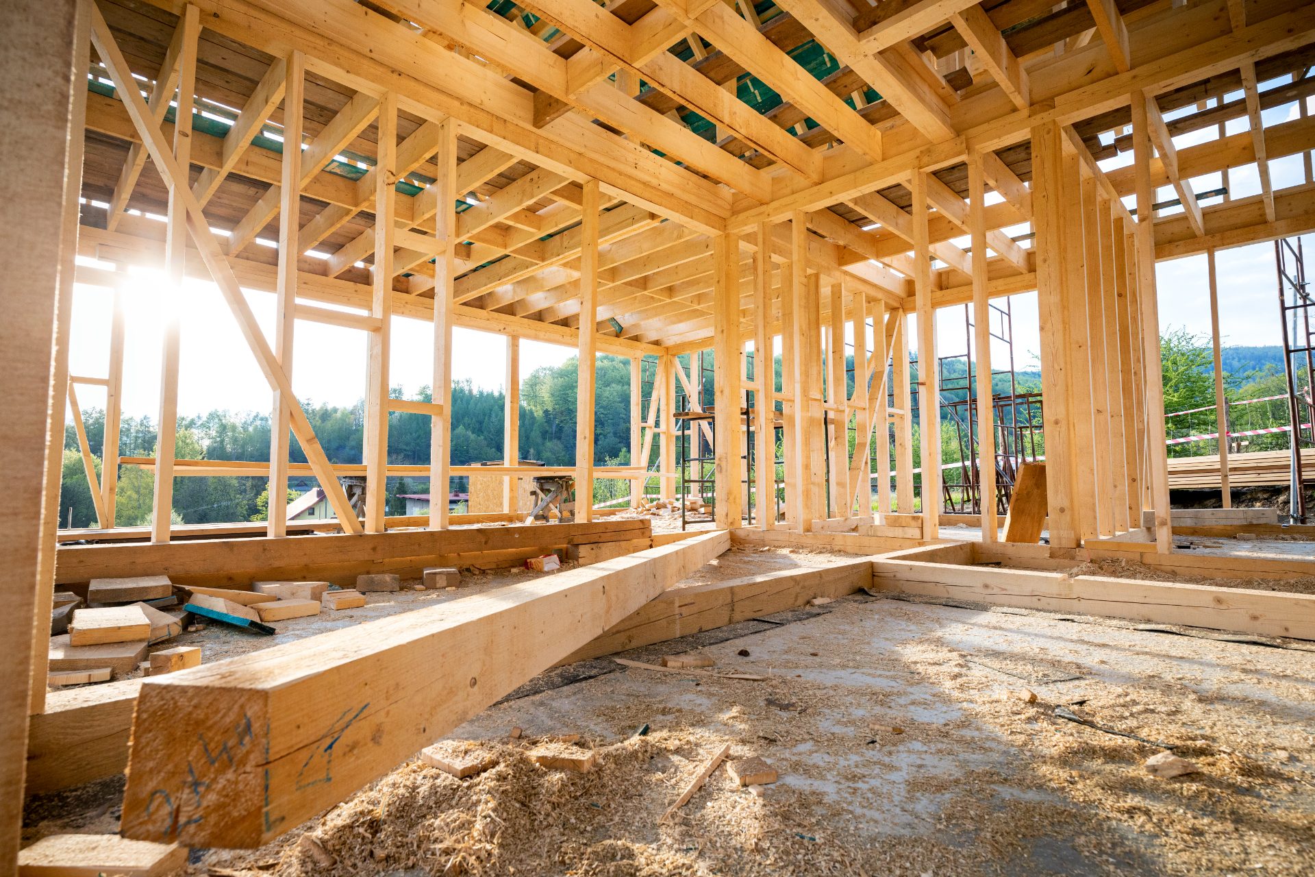 Interior of wooden-framed house under construction with exposed beams and mountain views